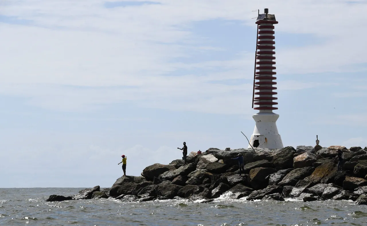 Fishermen fish while rescue teams search for victims of a shipwreck in Guiria, Venezuela on December 18, 2020. – At least 28 Venezuelan migrants died when a boat heading for Trinidad and Tobago sank, Attorney General Tarek William Saab said on Thursday. (Photo by YURI CORTEZ/AFP via Getty Images)