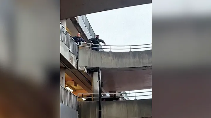 Police officers look down from an upper level of a Heathrow Airport parking garage while searching for suspects in a pepper-spray assault. (Tom Bate/Reuters)