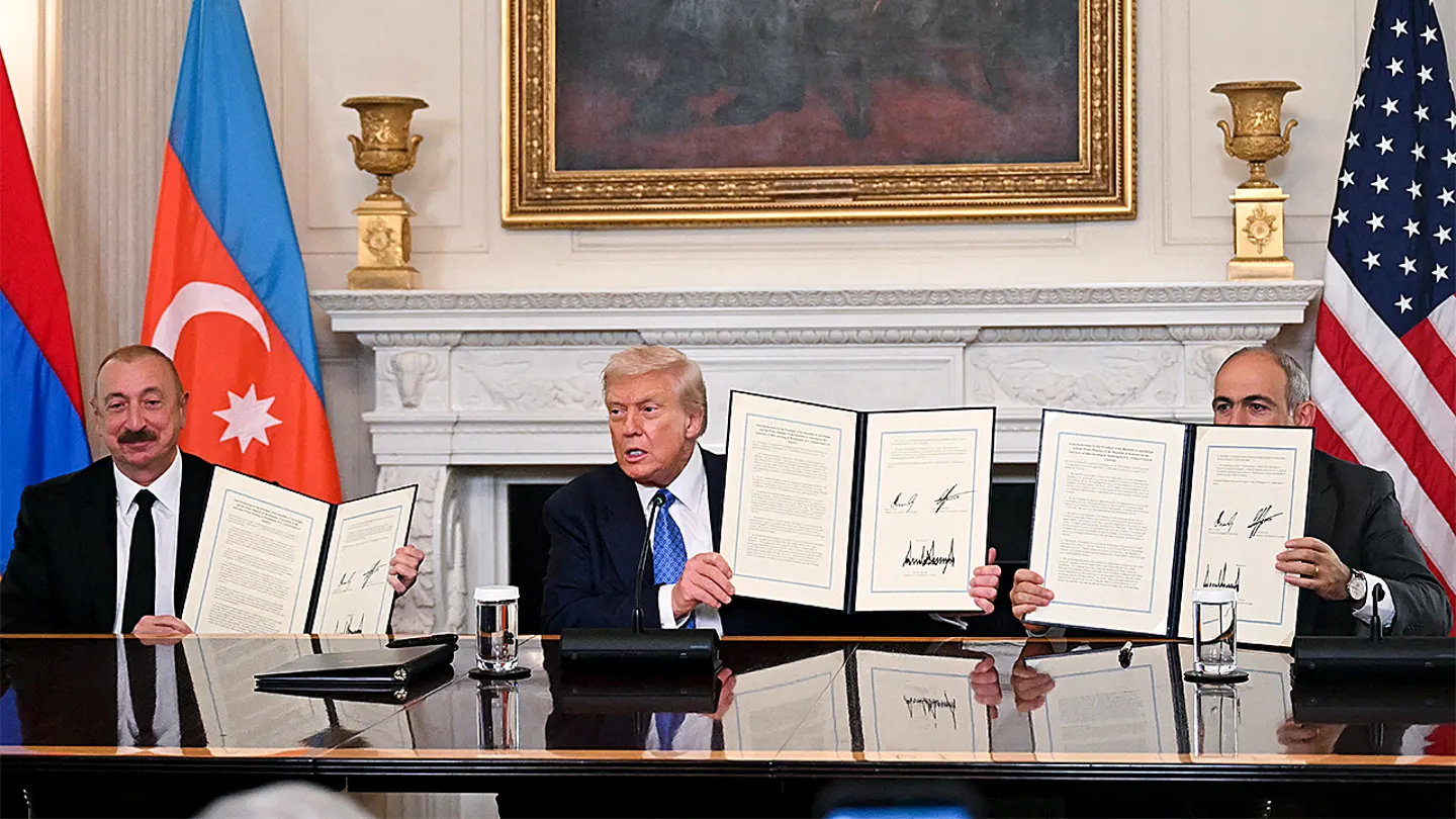 US President Donald Trump (C), Azerbaijani President Ilham Aliyev (L) and Armenian Prime Minister Nikol Pashinyan display the agreement they signed in the State Dining Room of the White House in Washington, D.C., on Aug. 8, 2025.  (Photo by Andrew Caballero-Reynolds/AFP via Getty Images)