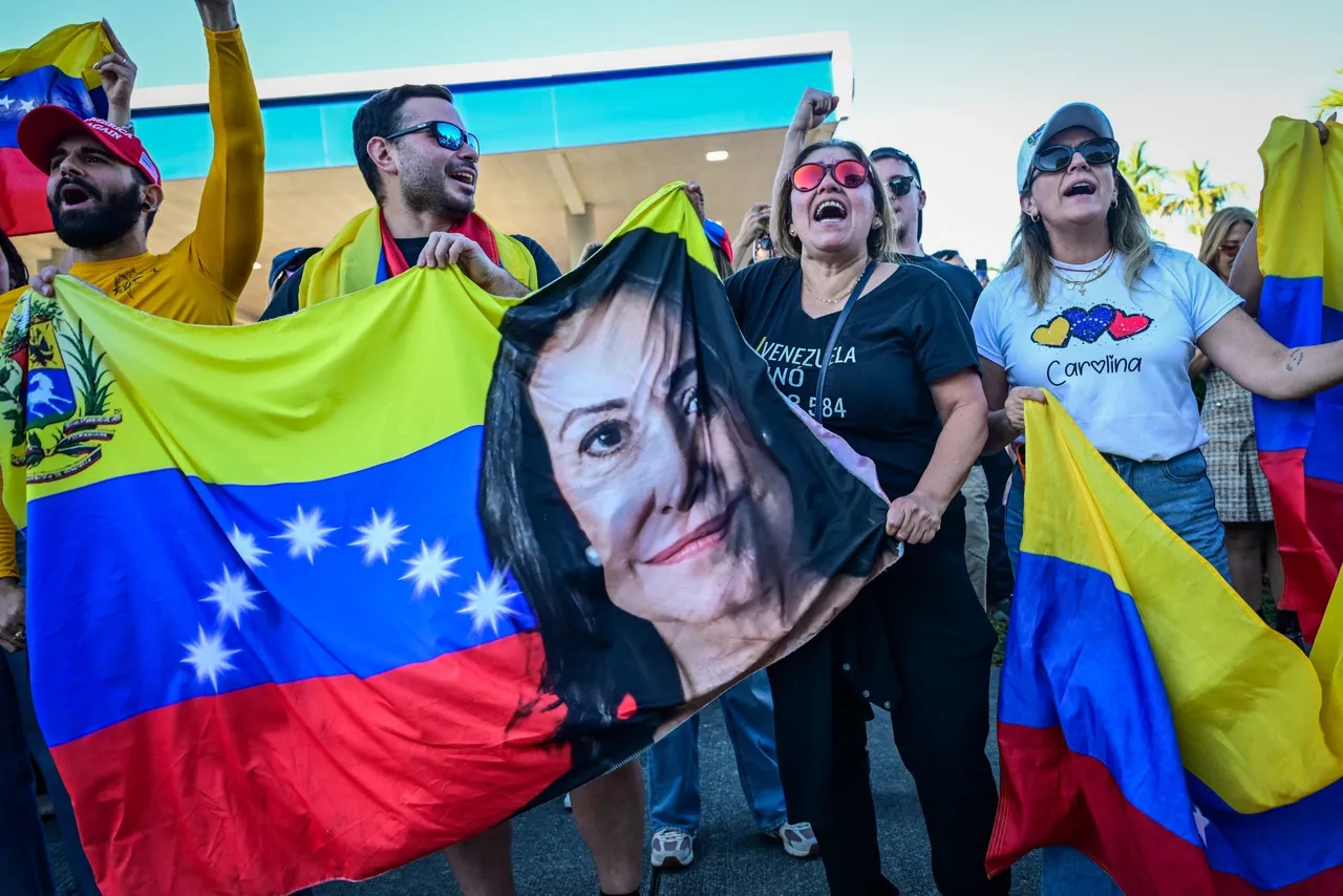 People in Doral, Florida, near Miami, hold a Venezuelan flag with a picture of opposition leader Maria Corina Machado as they react to the U.S. capture of Venezuelan dictator Nicolas Maduro, January 3, 2026. (Photo by Georgio Viera / AFP via Getty Images)