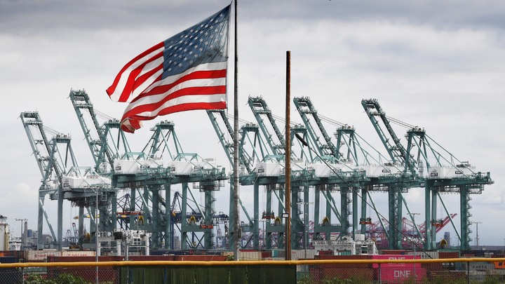 The U.S. flag flies over shipping cranes and containers in Long Beach, Calif. (Mark Ralston/AFP/Getty Images)