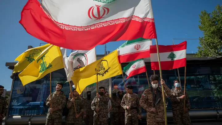 Members of the Basij paramilitary force hold Iranian flag, Lebanese flag, flag of Hashd Shabi, flag of Quds force's Fatemiyoun Brigade and flag of Lebanon's Hezbollah, during a rally commemorating International Quds Day, also known as the Jerusalem day, in downtown Tehran, April 14, 2023.   (Morteza Nikoubazl/NurPhoto via Getty Images)