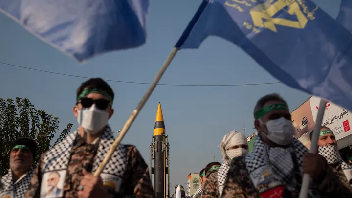 Islamic Revolutionary Guard Corps (IRGC) military personnel are standing at attention wearing protective face masks while an Iranian Kheibar Surface-to-Surface missile is being unveiled during the Ela Beit Al-Moghaddas (Al-Aqsa Mosque) military rally in Tehran, Iran, on November 24, 2023. The IRGC is unveiling two new missiles during the rally.  (Morteza Nikoubazl/NurPhoto via Getty Images)