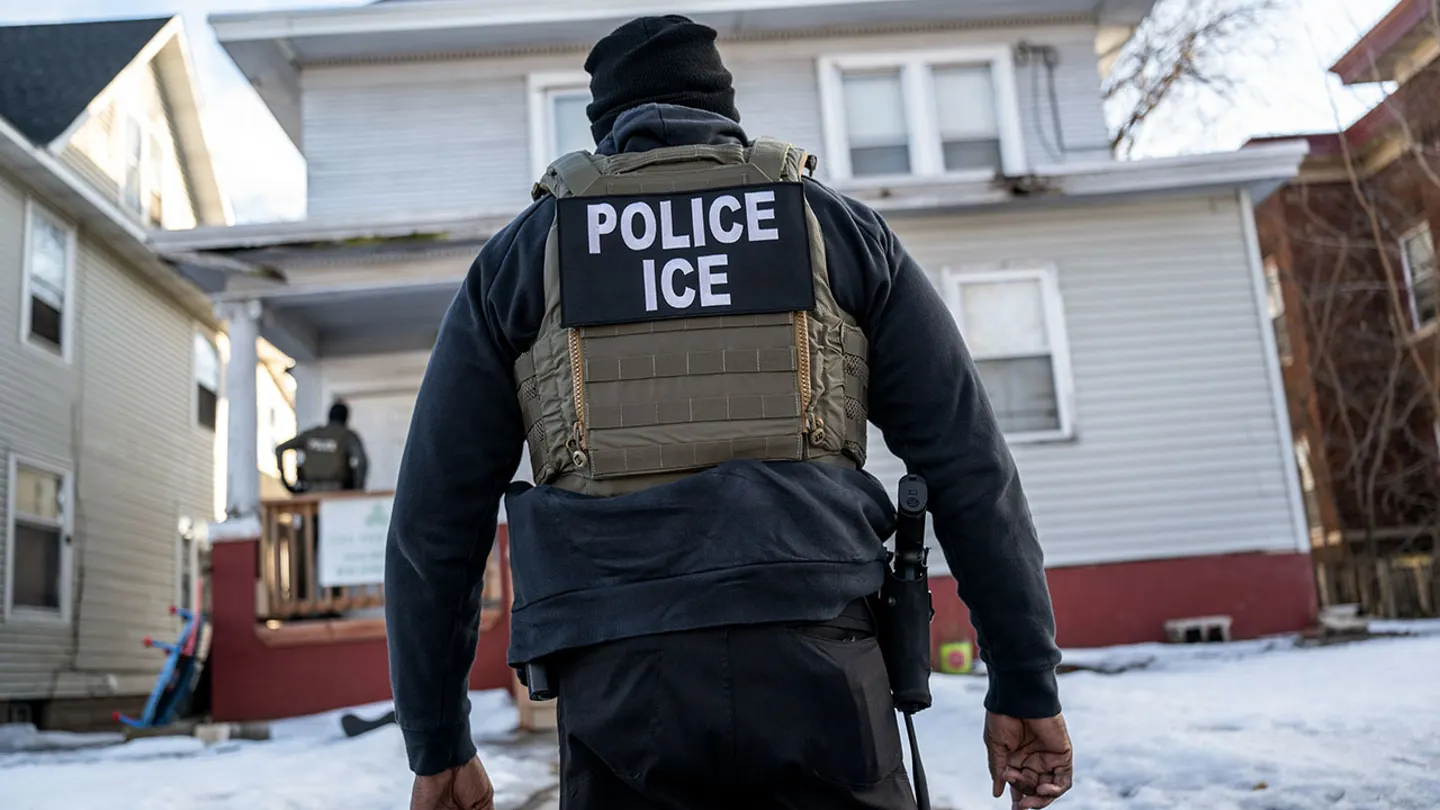 An ICE agent stands in front of a house.  (Victor J. Blue/Bloomberg via Getty Images)