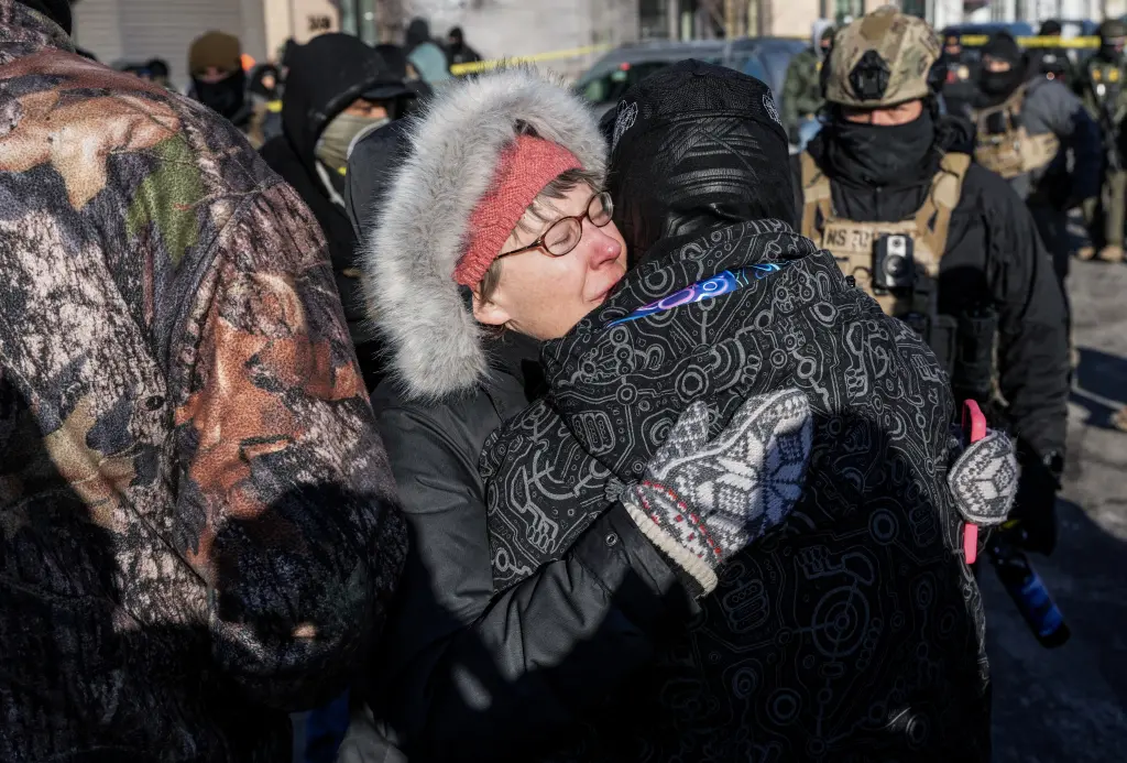 People hug each other at the scene of a shooting involving federal officers in Minneapolis, Minnesota, on January 24, 2026. REUTERS