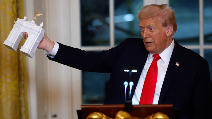 U.S. President Donald Trump holds a model of an arch as he delivers remarks during a ballroom fundraising dinner in the East Room of the White House on October 15, 2025. (Kevin Dietsch/Getty Images)