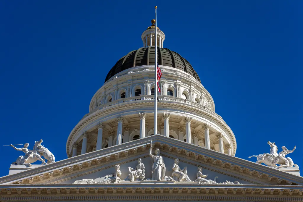 The dome of the California State Capitol in Sacramento, with detailed white sculptures and an American flag. Siegfried Schnepf &ndash; stock.adobe.com