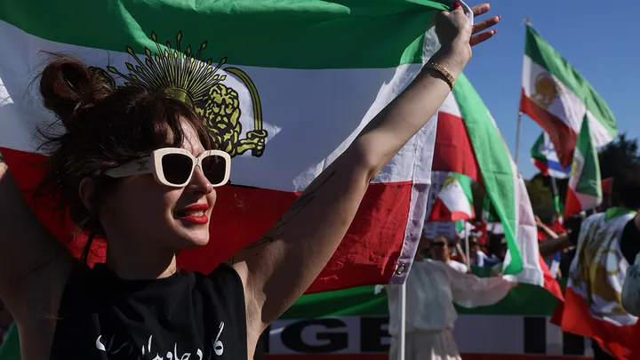 A woman holds up an Iranian flag as people celebrate the death of Khamenei in Los Angeles.  (Genaro Molina/Los Angeles Times via Getty Images)
