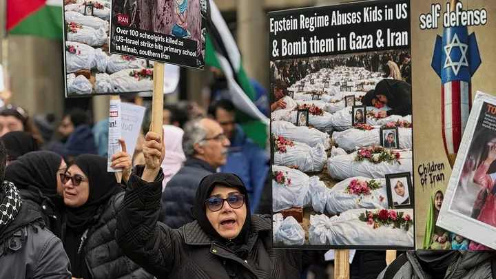 A counter-protester holds signs against the U.S.-Israel conflict with Iran near a rally by people supporting the war in front of the U.S. consulate in Toronto, Ontario, Canada, March 7, 2026.  (Kyaw Soe Oo/Reuters)