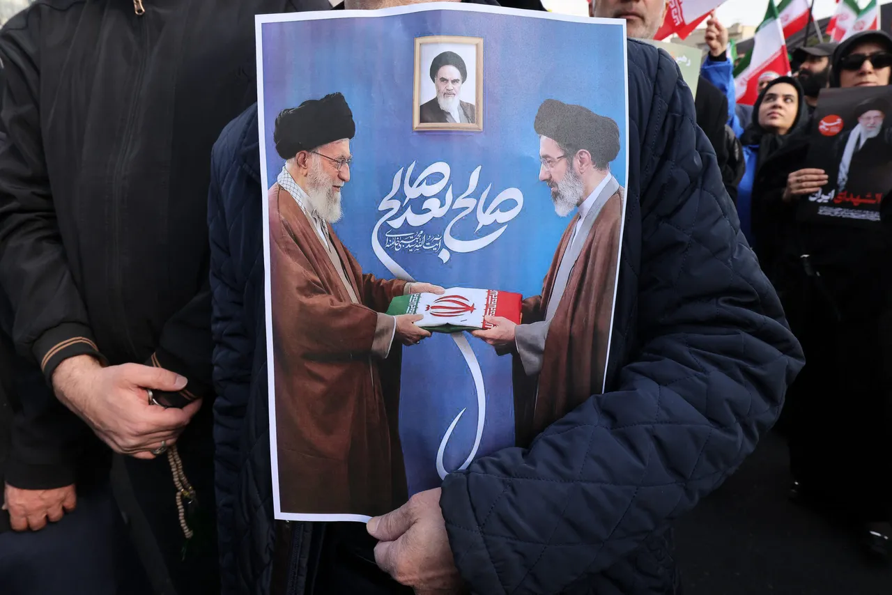 A man holds a picture of Iran&rsquo;s new Supreme Leader Ayatollah Mojtaba Khamenei (R) being handed over a folded Iranian flag by his late father Ali Khamenei (L), during a rally in support of him at Enghelab Square in central Tehran on March 9, 2026. (Photo by Atta Kenare / AFP via Getty Images)