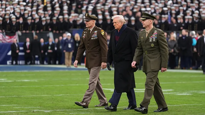 President Donald Trump is escorted onto the field to take part in the ceremonial coin toss before the start of a game between Army and Navy at M&T Bank Stadium in Baltimore Dec. 13, 2025. (Stephanie Scarbrough/AP Photo)