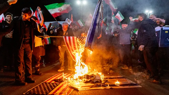 Iranians set fire to flags of the United States and Israel as they gather to commemorate those killed from the Dena naval vessel at Enghelab Square March 17, 2026, in Tehran, Iran. (Getty Images)