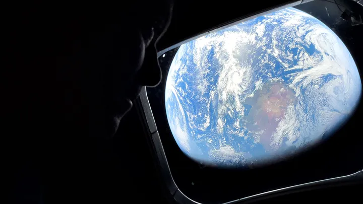 This image provided by NASA, astronaut and Artemis II Commander Reid Wiseman peers out of one of the Orion spacecraft's main cabin windows, looking back at Earth, as the crew travels towards the Moon on Thursday, April 2, 2026. (NASA via AP) (NASA via AP)