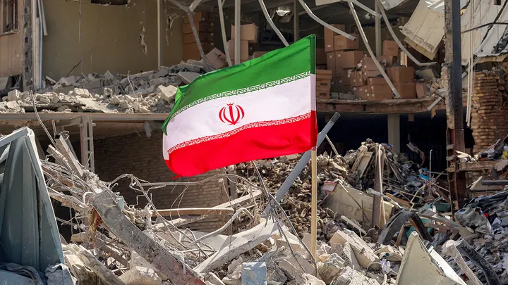 An Iranian flag is placed amid rubble next to a destroyed residential building near Ferdowsi Square in Tehran on March 3, 2026. (Atta Kenare/AFP)