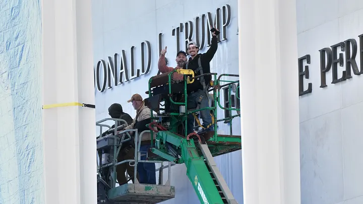 Workers install Donald J. Trump signage above the existing Kennedy Center sign in Washington, D.C., on Dec. 19, 2025. (Jacquelyn Martin/AP)